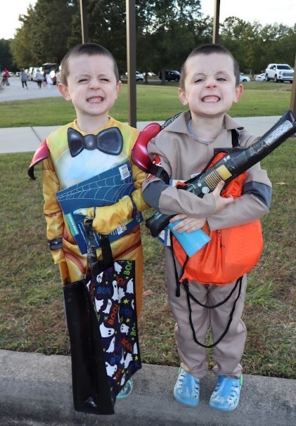 Two twin brothers dressed in halloween costumes with big smiles. 
