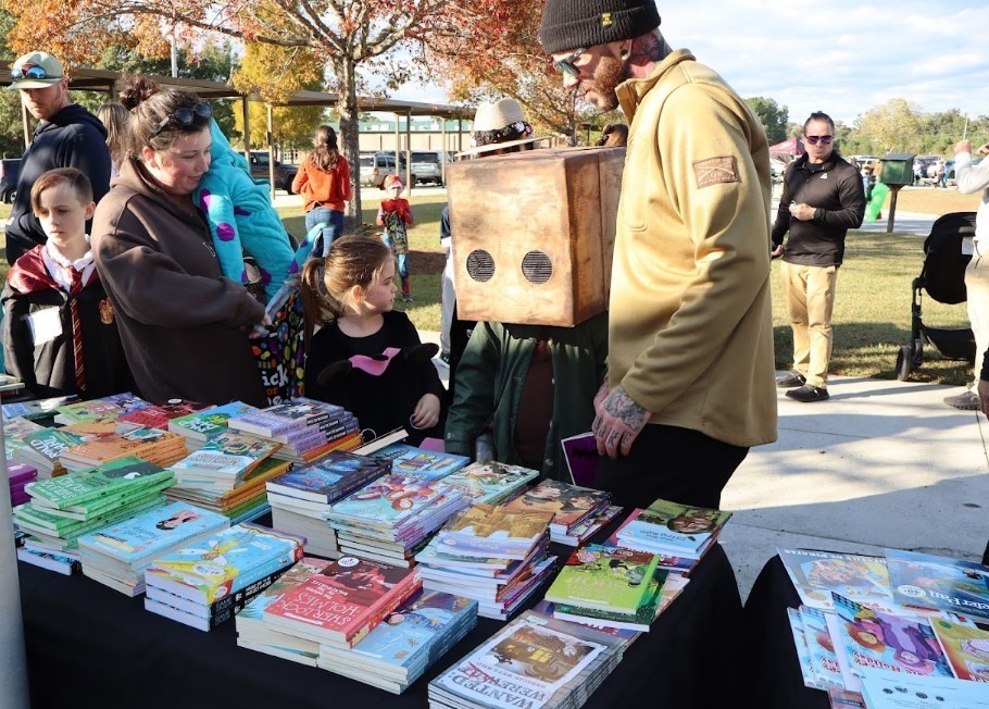 Families gathered around a table of books.