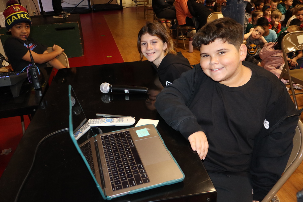 Two students sitting behind computers and ipads operating all sound components for our show. 