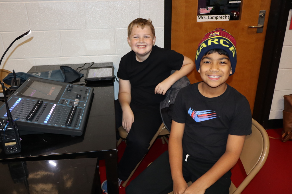 Two student sitting behind a light board operating the lights at our third grade performance. 