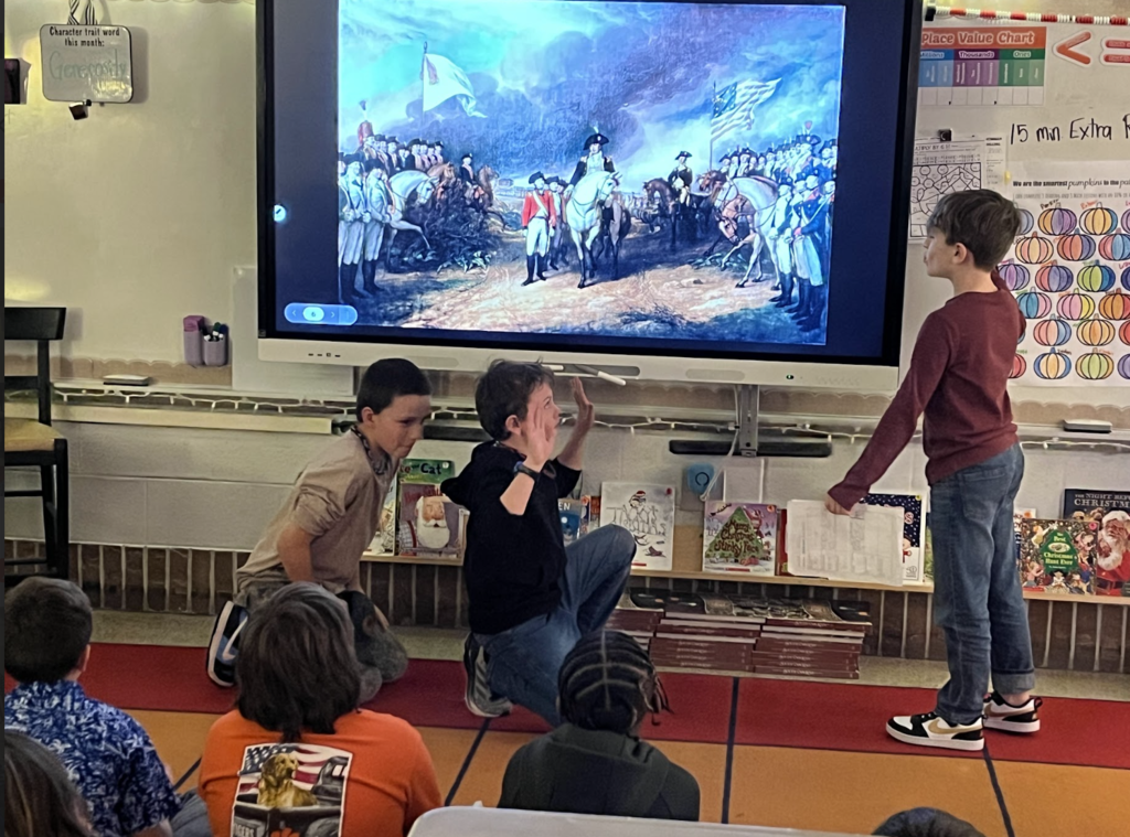 Three students presenting a battle from the revolutionary war in front of an image from the battle of Yorktown.