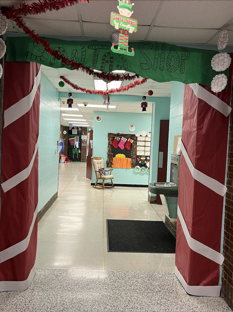 SANTA'S SHOP / SANTA'S ELVES bulletin display with the phrase 'See Everything' beneath, part of a festive hallway decoration.