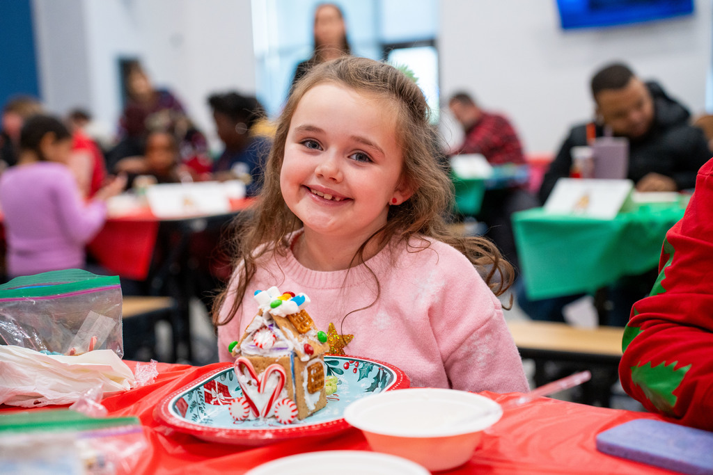 student smiling with gingerbread house