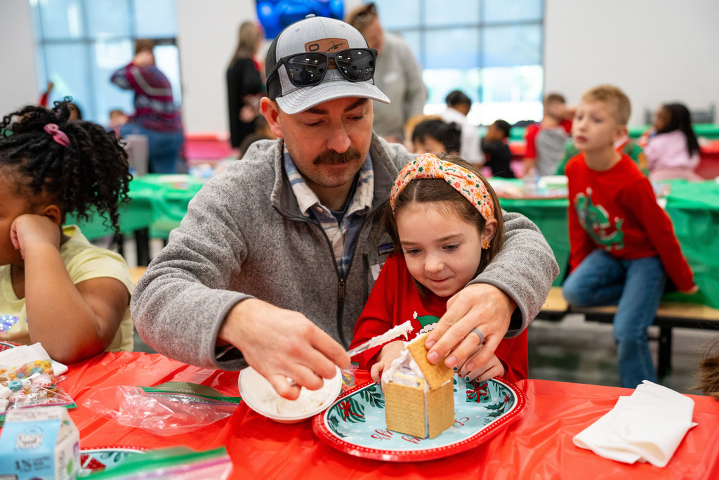 dad helping student make gingerbread house