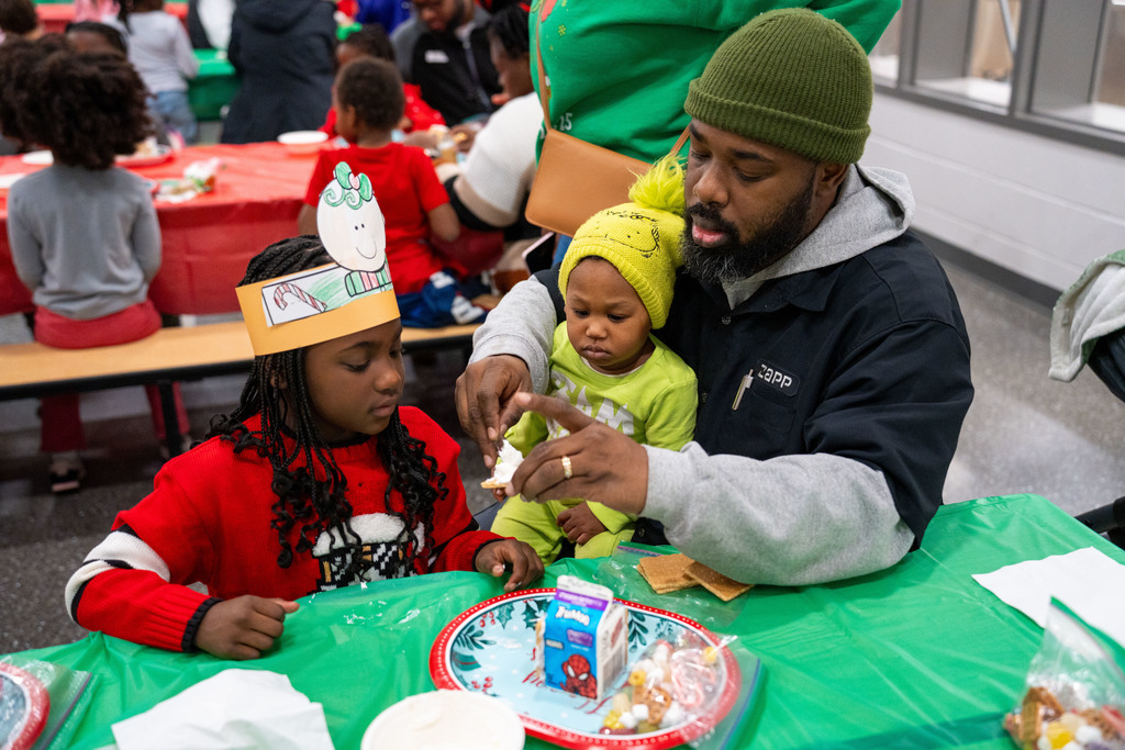 dad helping student make gingerbread house