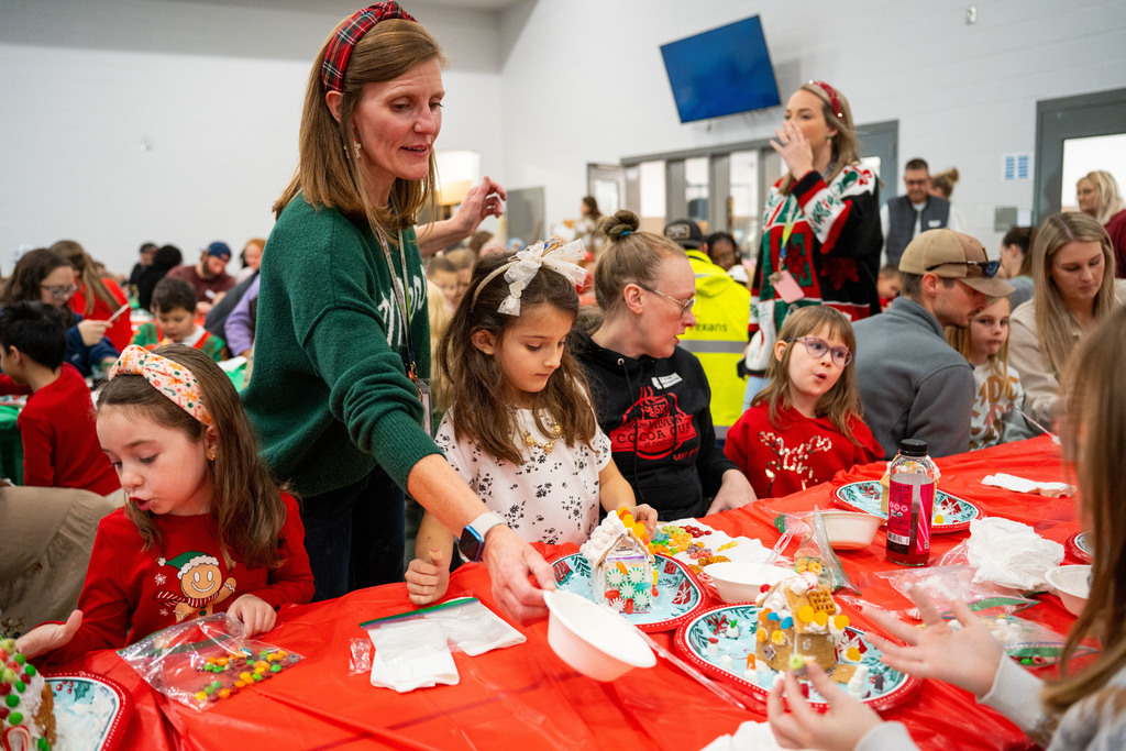 teacher helping students make gingerbread houses