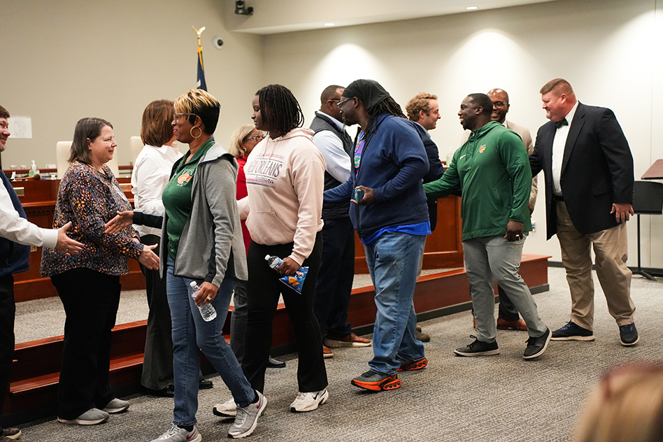 Desmond Green's family and coaches shaking board members hands