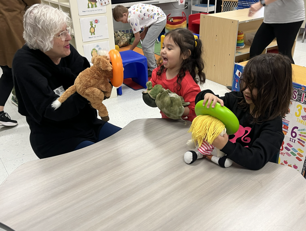 Two students holding puppets interacting with artist Becky Becker! 