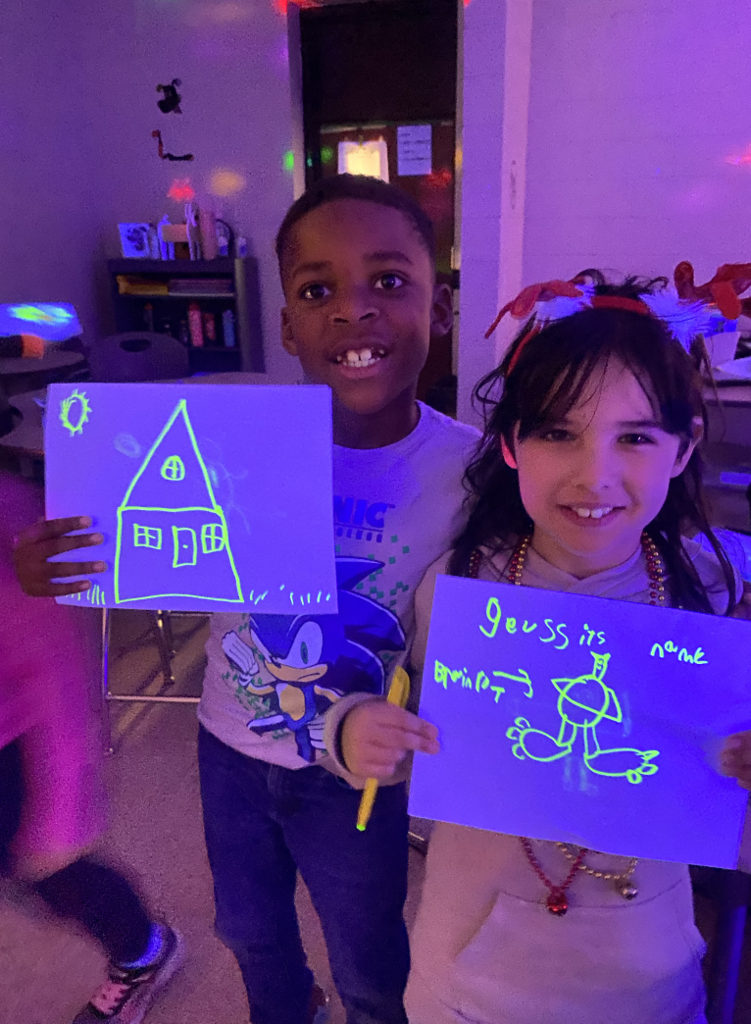 Students holding glow in the dark pictures they had created