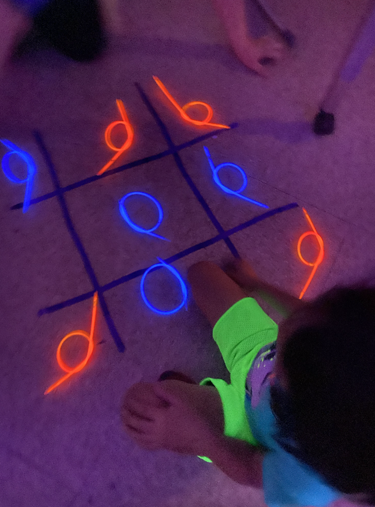 Student playing tik tack toe with glow bands