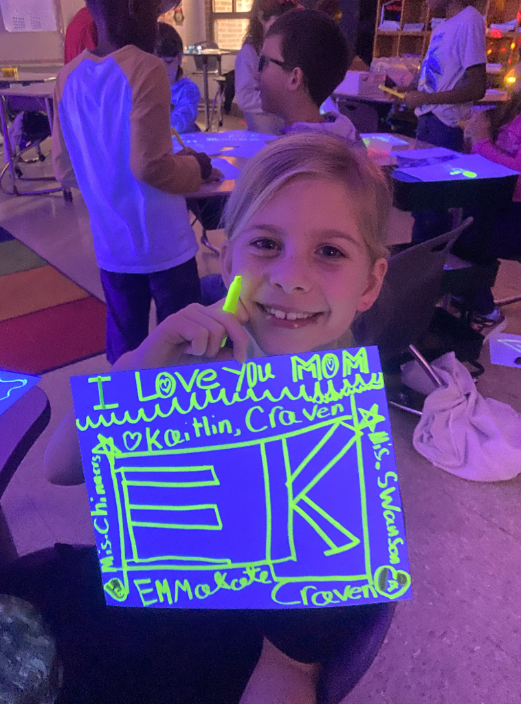 Student holding a glow in the dark poster she had made