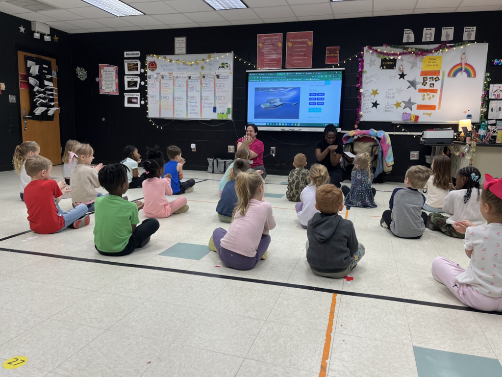 Students sitting on the floor making crocodile hands with the K5 resident- The Charleston Stage, 