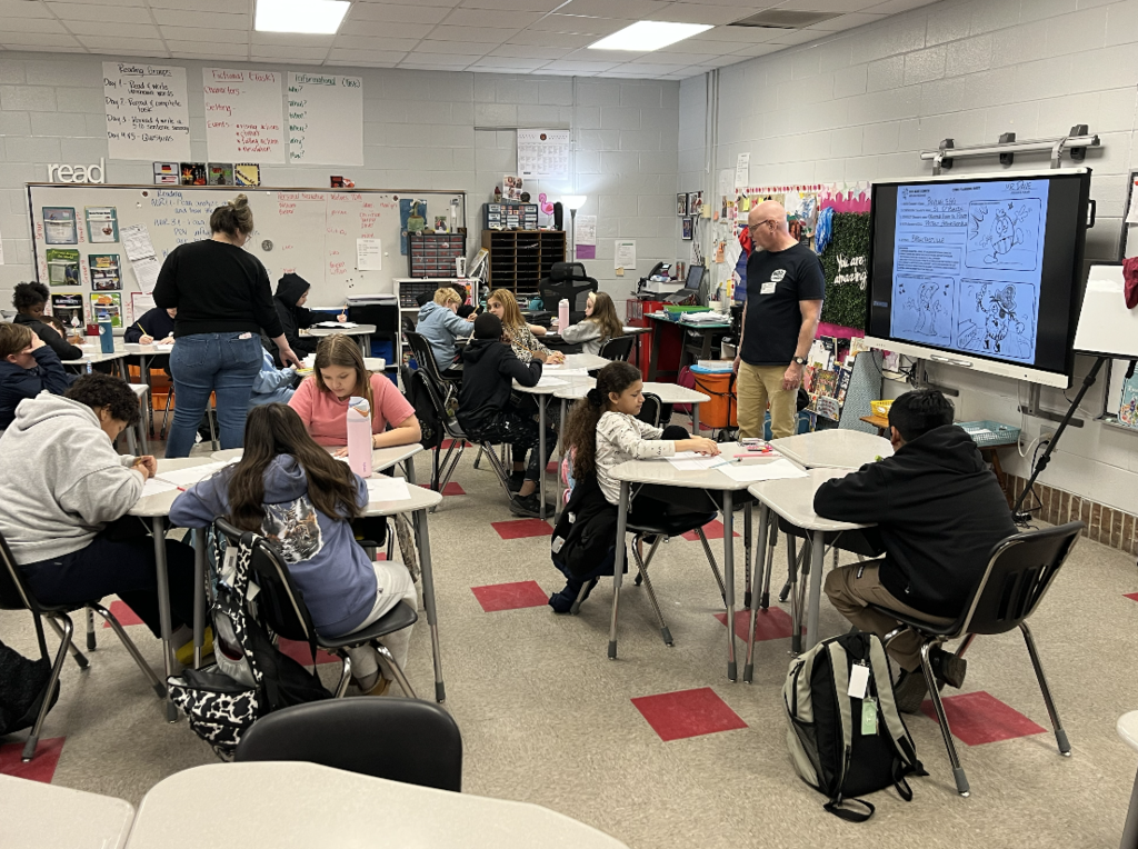 Students sitting at their desk while artist in residence Dave McDonald gives instructions 