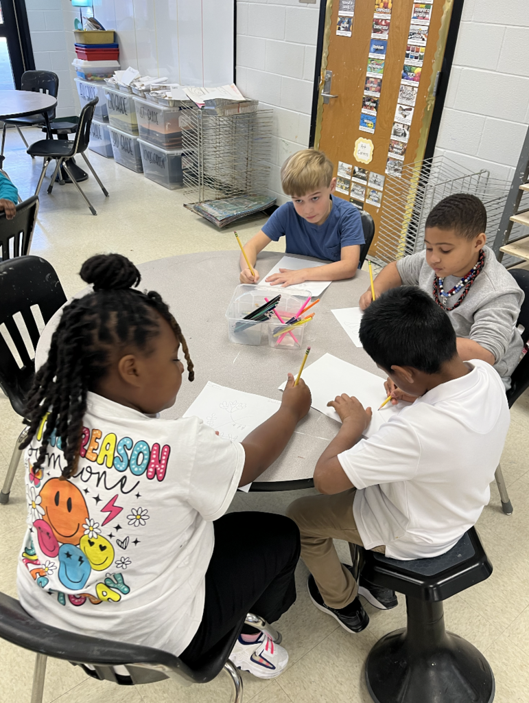 Students sitting at a table doing a drawing of an indigo plant