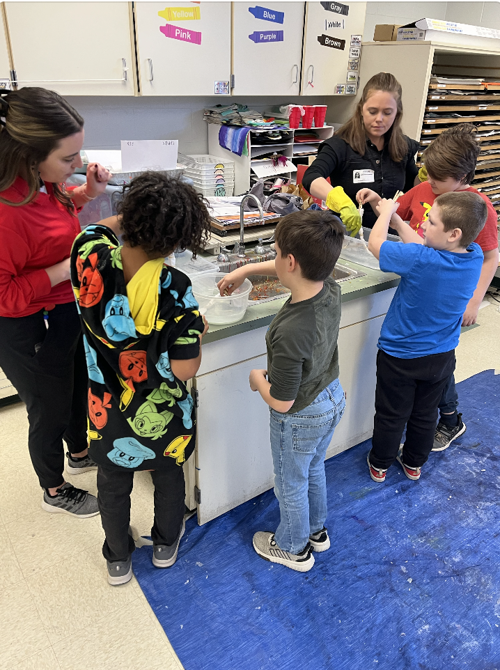 4 students standing around a sink rinsing their cloth for their indigo art. 