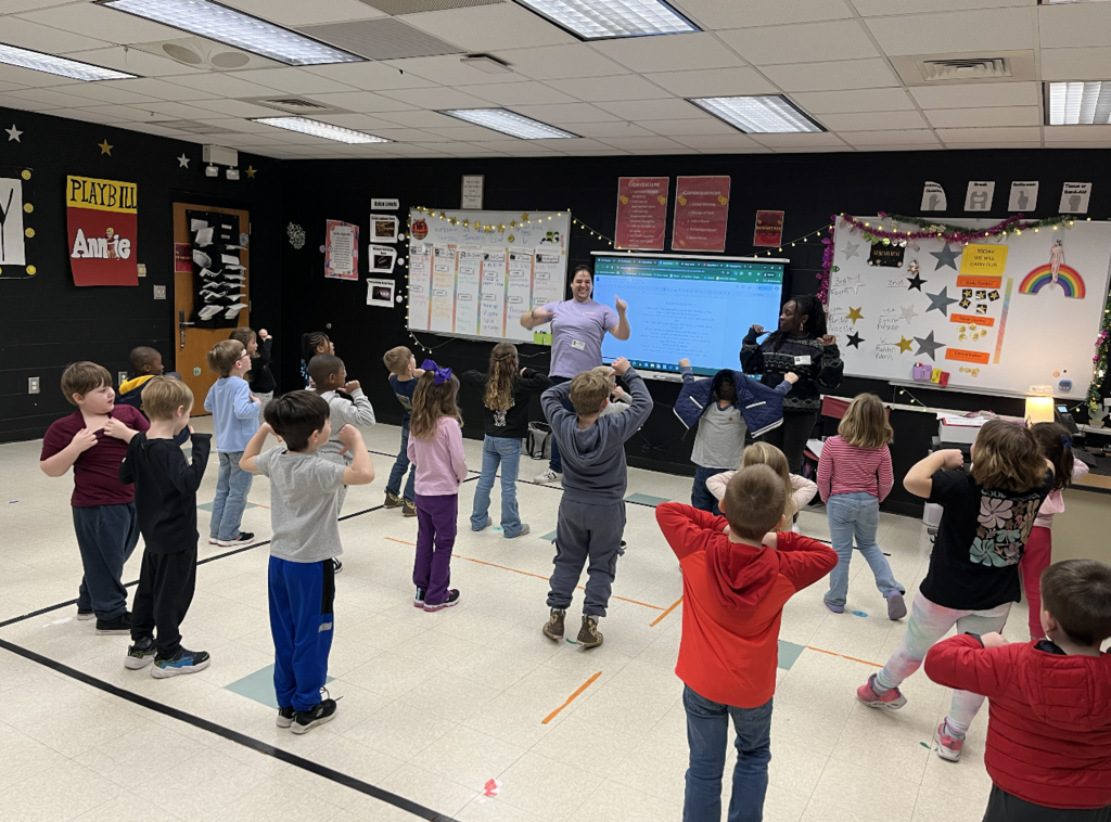students in the drama room elbows bent over head 