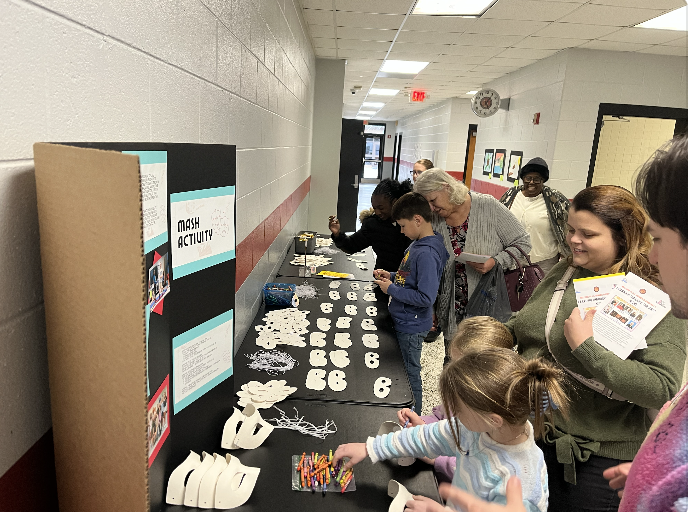 Families standing in the hallway creating masks. 