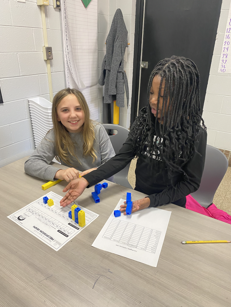 Two students working on their graphs with yellow and blue unit cubes 