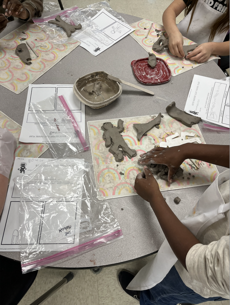 This image shows hands of students modeling clay into Keith Haring figures.