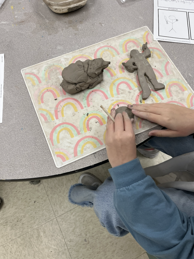 This image shows one set of hands molding clay into a ball.