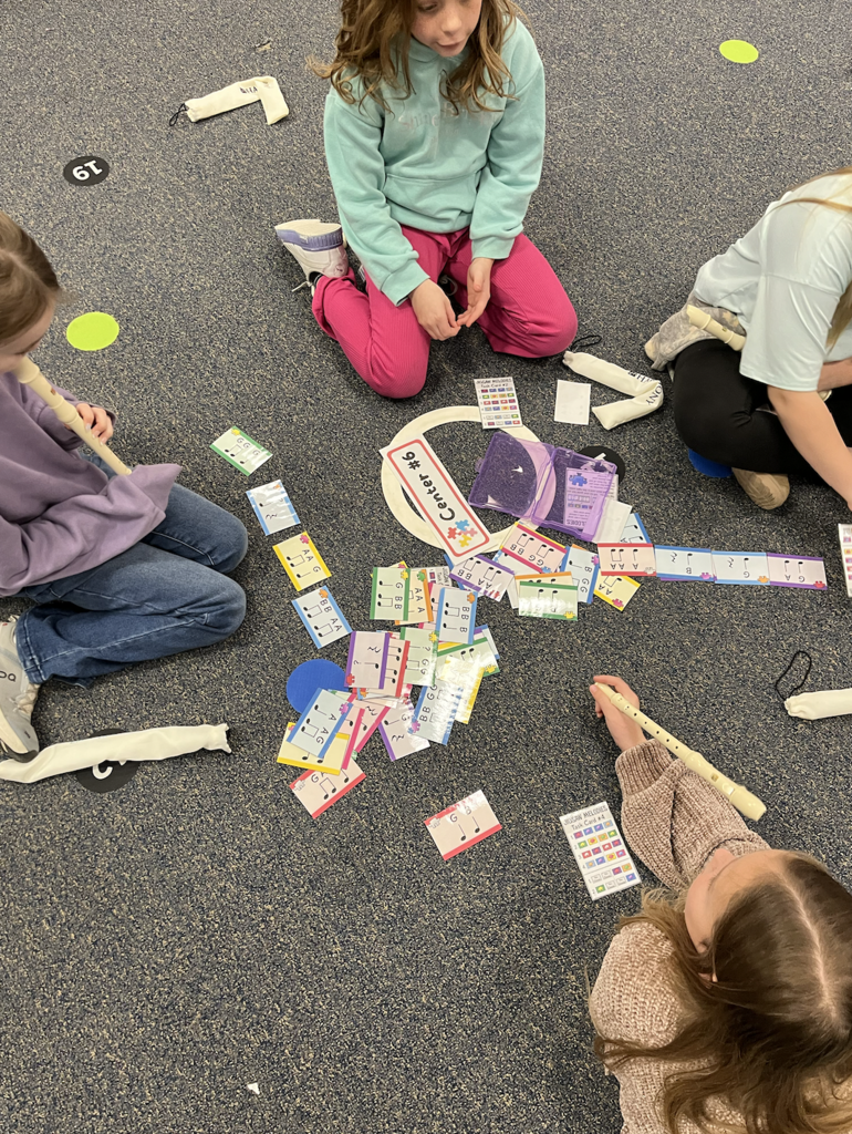 This picture shows a recorder center, flashcards are displayed on the floor, students have their recorders and are working together