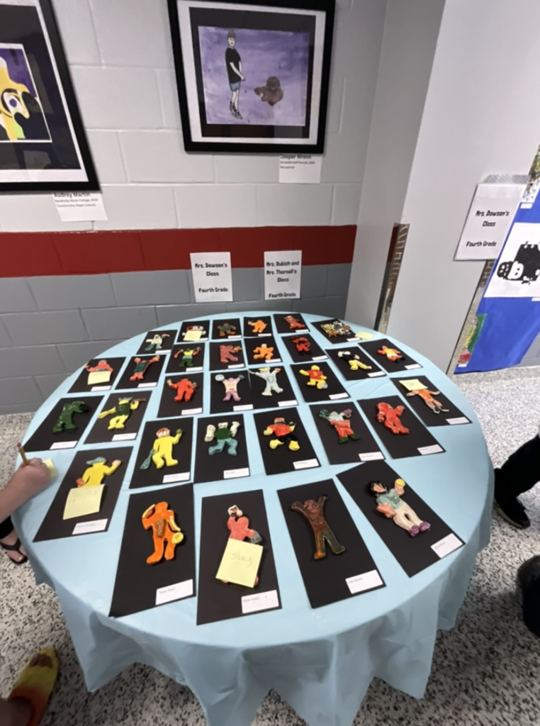 A table with blue cloth that has many pieces of clay artwork on display