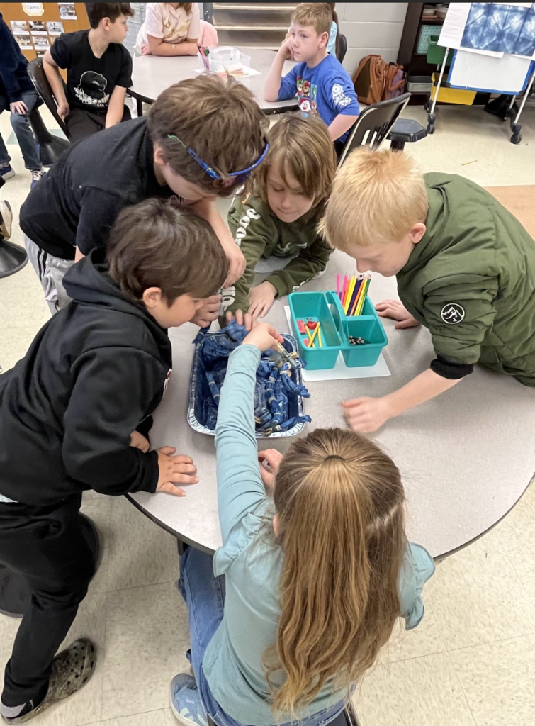 Students sitting around a table dyeing pieces of fabric with indigo