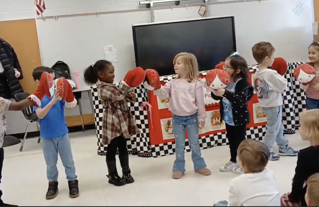 Students playing with red and white puppets
