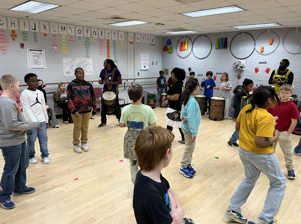 Students standing in the dance room working with artists