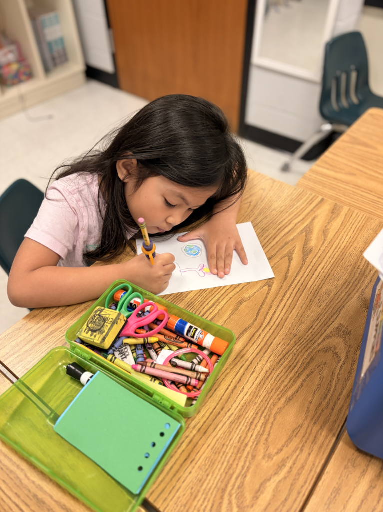 Student sitting at desk coloring with pencil case sitting next to student