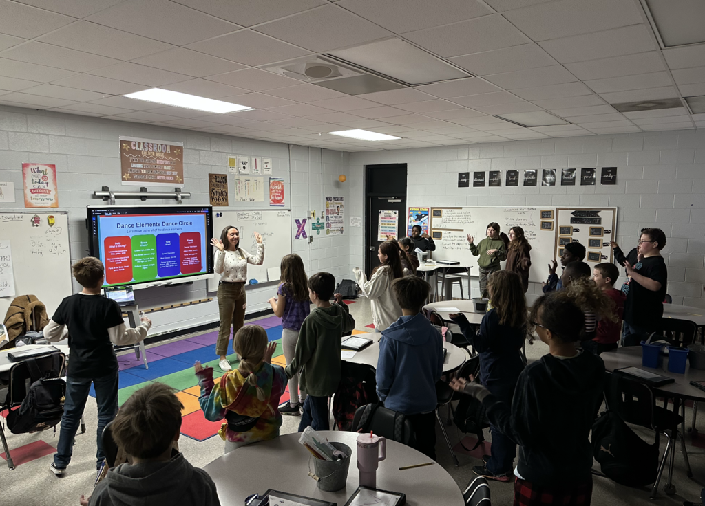Students standing in classroom moving their arms over head