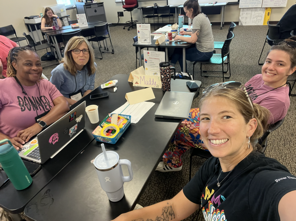 4 teachers sitting a table with markers and pens