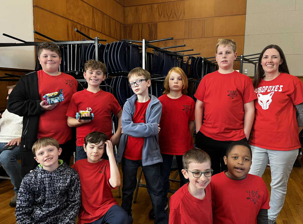 Students in red robo foxes tee shirts, Robotics team posted in two rows