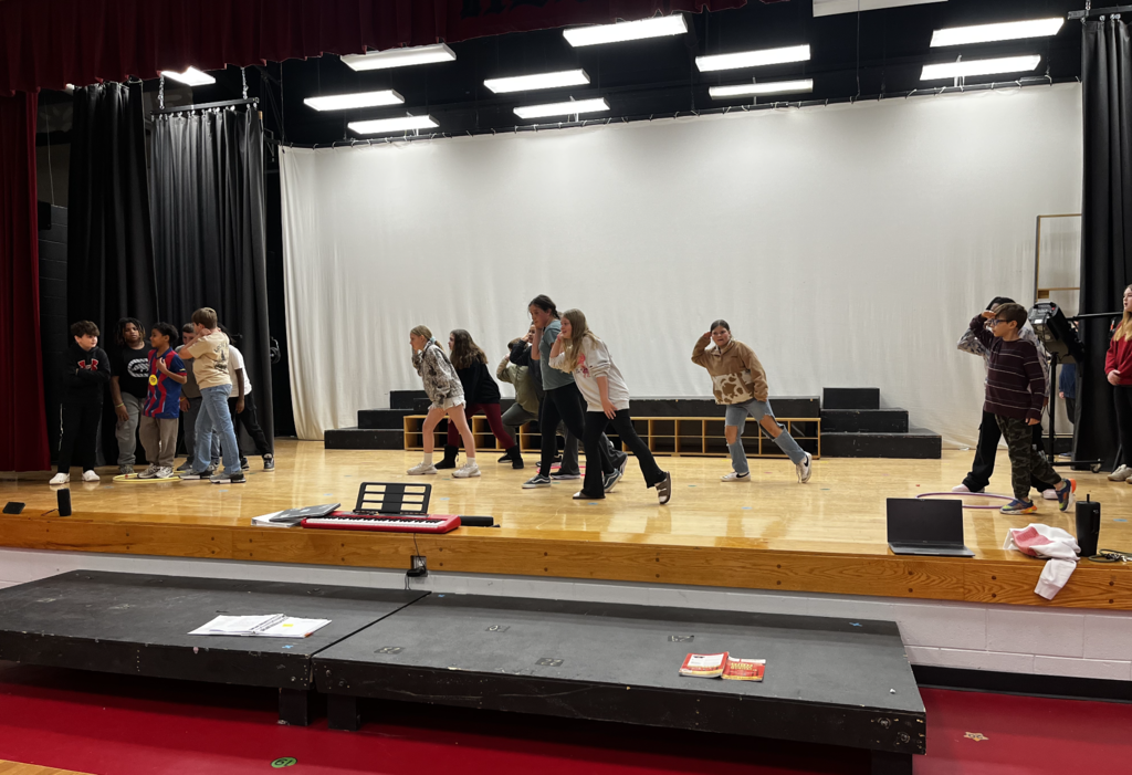Students leaning and lounging to stage left in clumps of 5-6