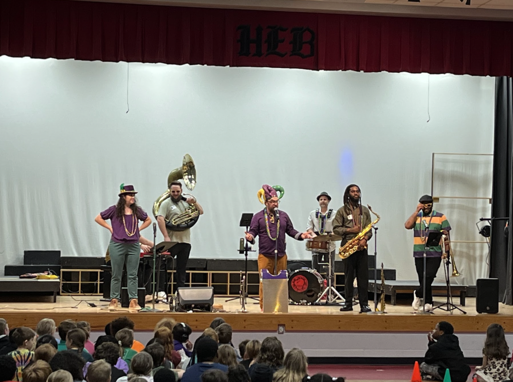 This photo features all7 band members holding their instruments (tuba, trumpet, saxophone, trombone, snare drum, piano and vocalist)
