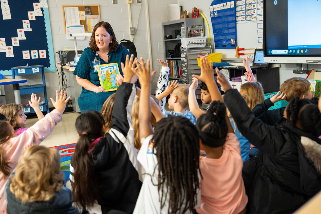 Jen Croley with students raising hands