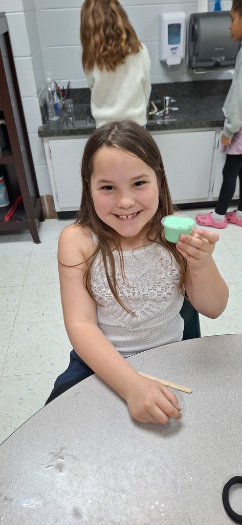 One student smiling with their mint green slime