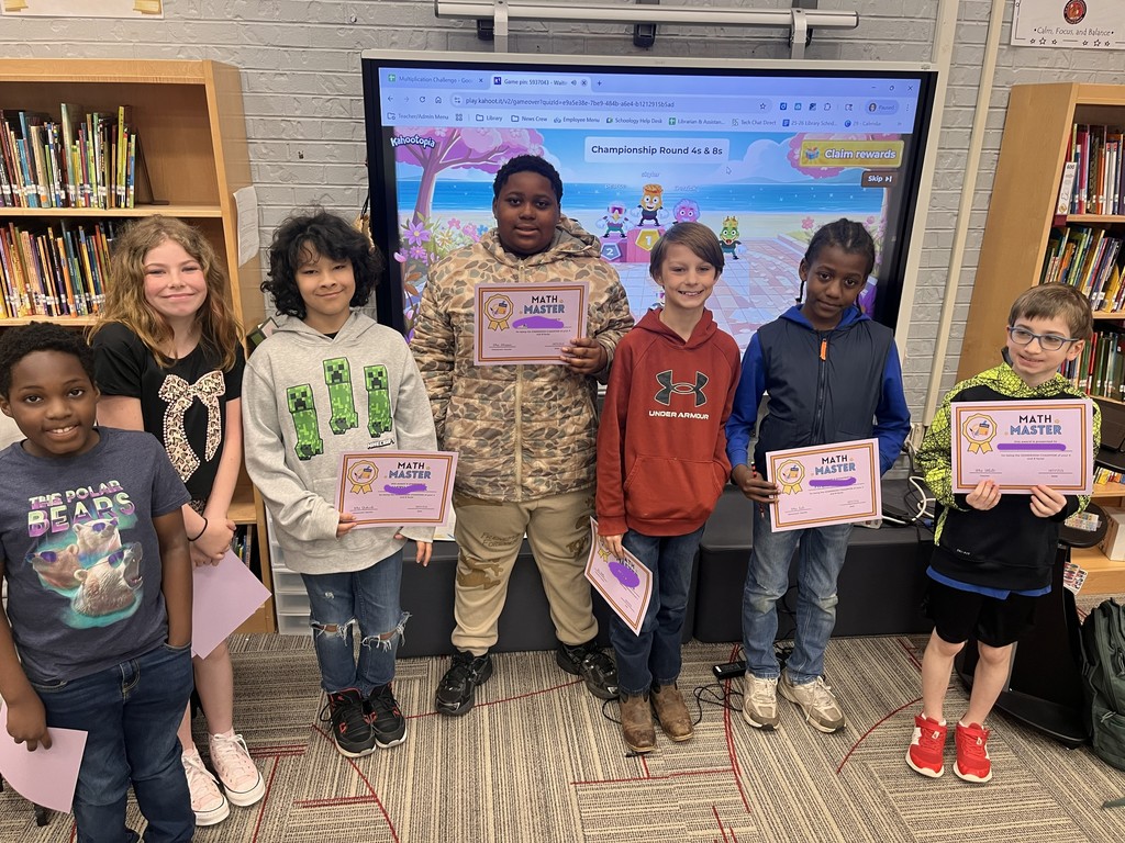 Five 4th grade Math Master certificate winners posing in front of a Kahoot Championship Round 4s & 8s digital display screen in the school library