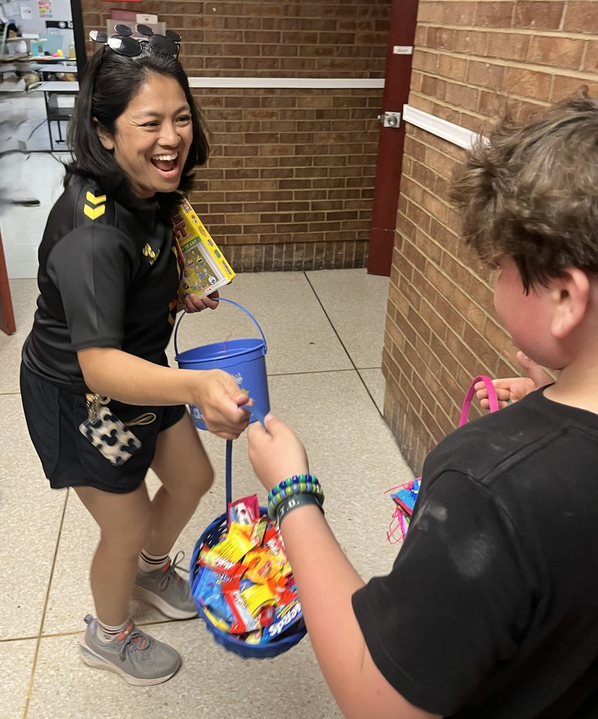 Woman in athletic clothing holding a bucket of snacks hands it to a boy with bracelets.