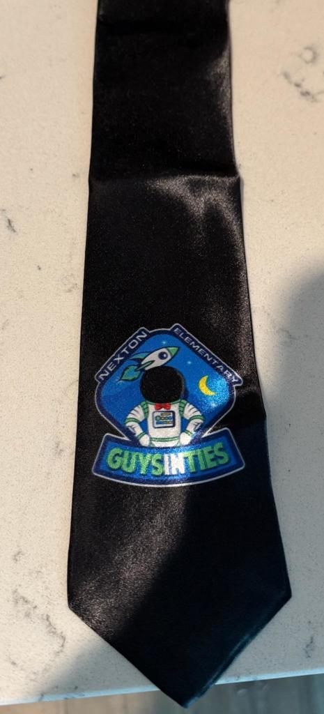 A black tie with a blue emblem featuring a cartoon astronaut, a rocket, and a crescent moon, with "GUYSINTIES" written in blue letters.
