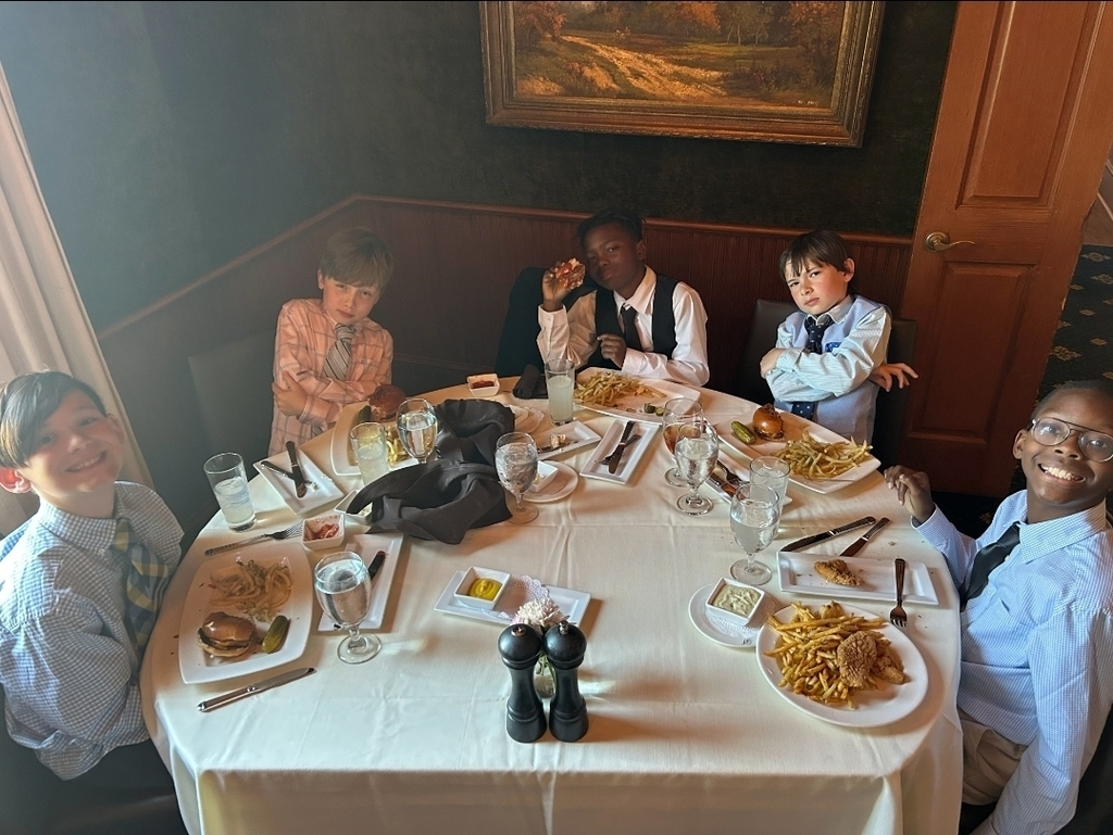 Group of people seated around a table with various food items, drinks, and tableware.