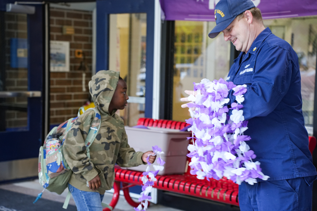 military member handing student necklace