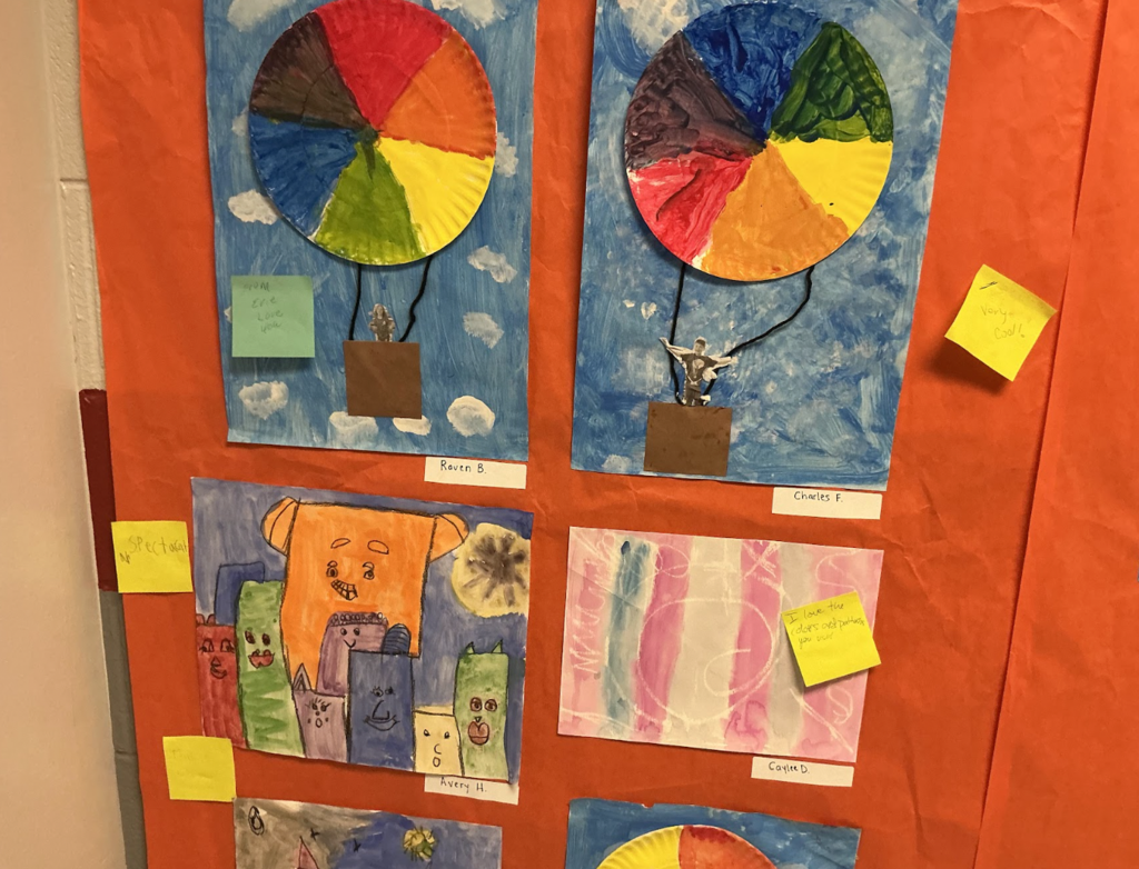 An art display with colorful artwork, including two circular designs, an orange dog, and a cityscape.