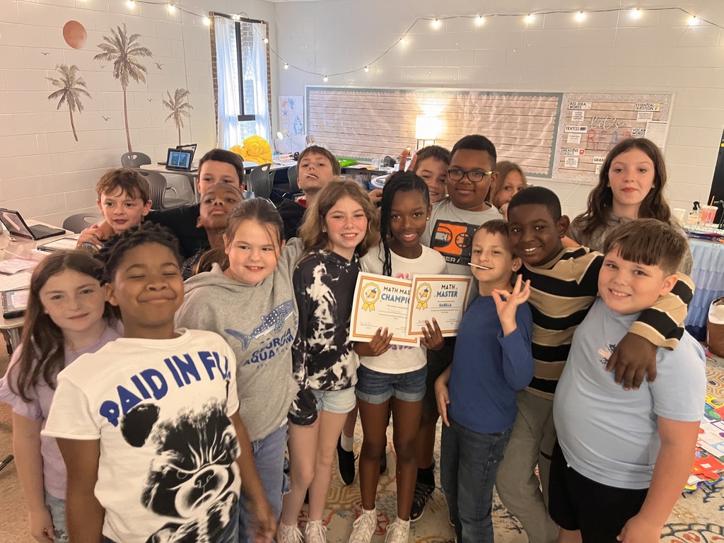 A group of children in a classroom with certificates in hand, smiling for a photograph.