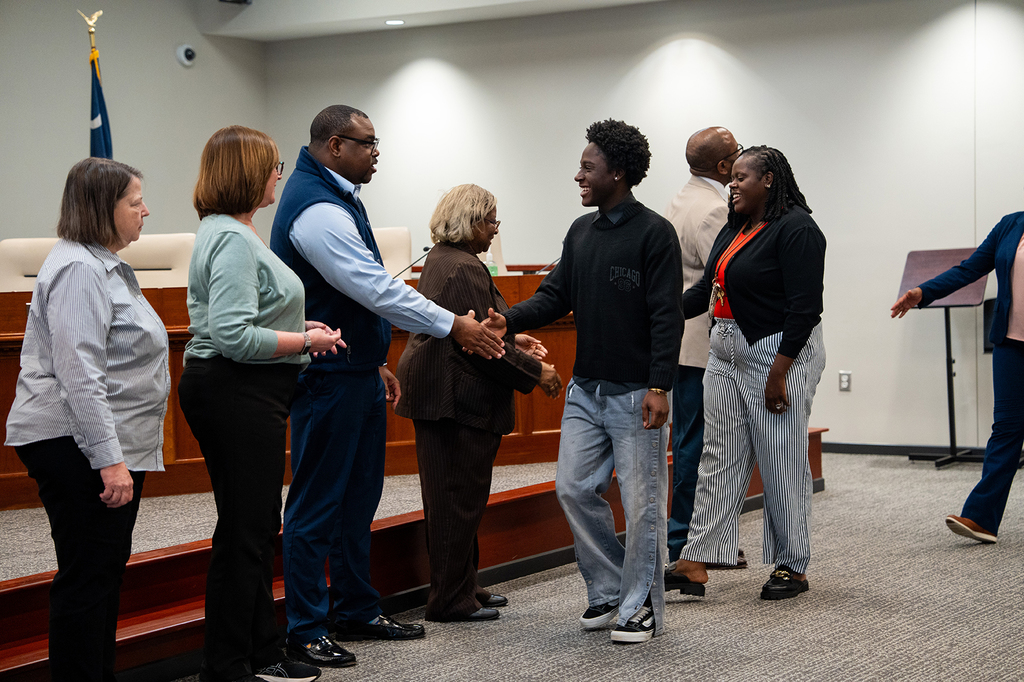 Cross High student shaking hand with board members