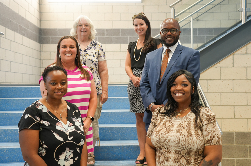 Six adults standing on stairs. 