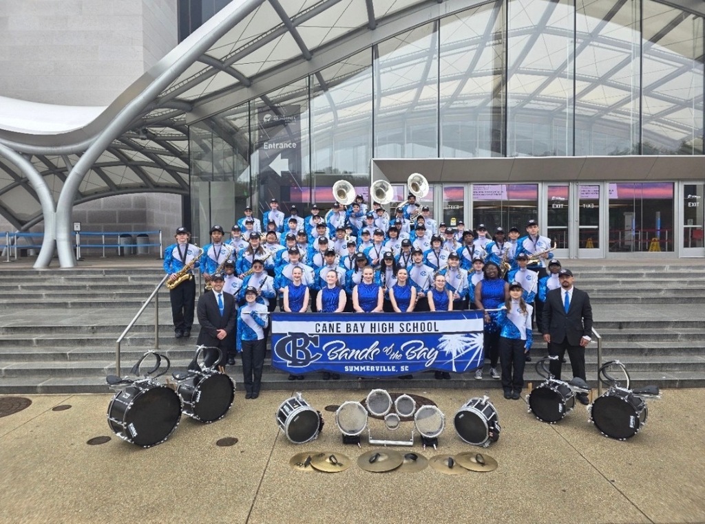 Cane Bay High marching band stands in front of a building for a group picture