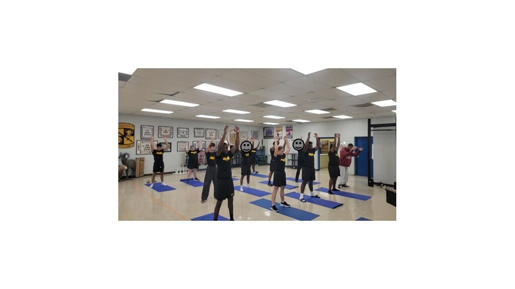 Multiple people in workout clothes doing yoga poses in a room with white walls and ceiling.