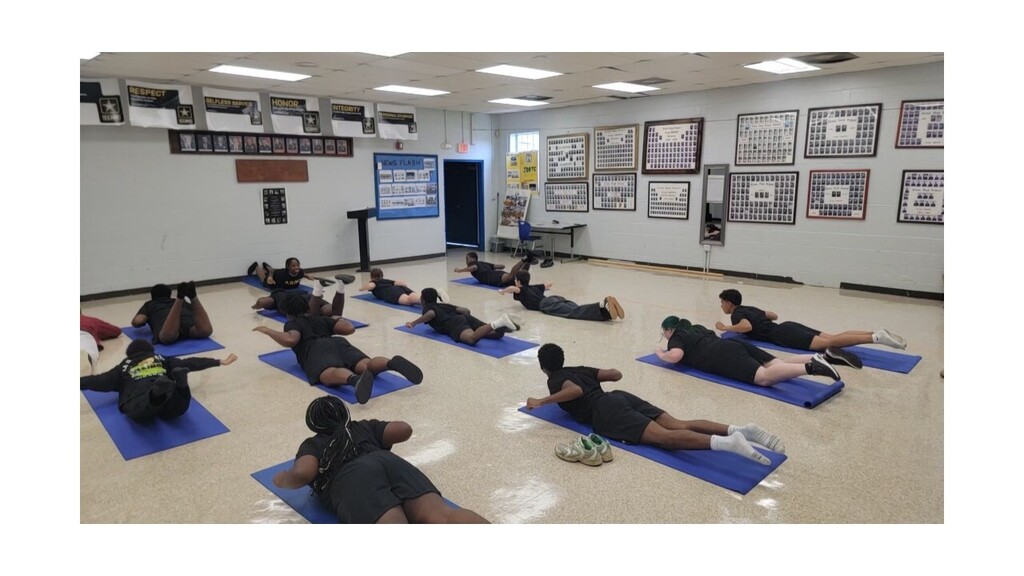 A group of people doing exercises on mats in a room with framed pictures on the wall.