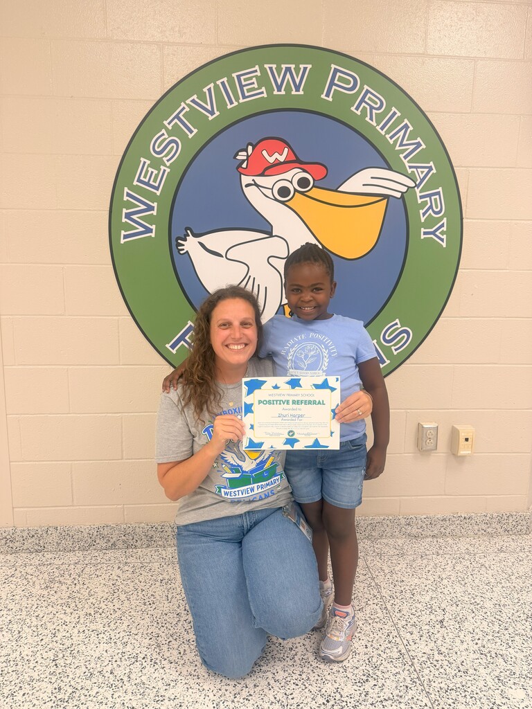 Woman crouches, holding a child in front of a Westview Primary logo. Child holds certificate.
